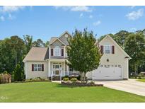 Charming two-story home featuring a well-manicured lawn and attached two-car garage at 142 Scarlet Oak Run, Clayton, NC 27520
