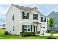Charming two-story home featuring stone accents, a two-car garage, and a well-maintained lawn at 1476 Burgundy Bluff Ln, Zebulon, NC 27597