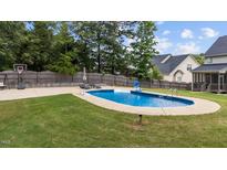 A beautiful in-ground swimming pool is surrounded by a large concrete patio and lush green lawn at 149 Great Oak Dr, Garner, NC 27529