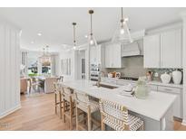 Bright kitchen with white cabinets, quartz countertops, oversized island, and pendant lighting at 160 Serene Xing, Fuquay Varina, NC 27526
