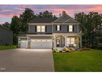 Charming two-story home boasts a three-car garage, welcoming porch, and meticulously landscaped front yard at 165 Hickory Grv Dr, Sanford, NC 27330