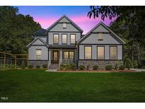 Charming two-story home showcasing a beautifully landscaped yard, stone accents, and a welcoming front porch at 1809 Bowling Rd, Fuquay Varina, NC 27526