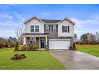 Charming two-story home with gray and white siding, a two-car garage, and a manicured lawn at 21 Whistling Way # 17, Lillington, NC 27546