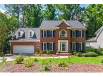 Charming two-story brick home with manicured lawn and blue shutters surrounded by lush greenery at 4309 Omni Pl, Raleigh, NC 27613