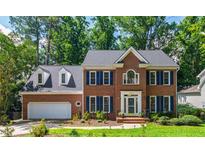 Charming two-story brick home with blue shutters, a well-manicured lawn, and lush landscaping at 4309 Omni Pl, Raleigh, NC 27613