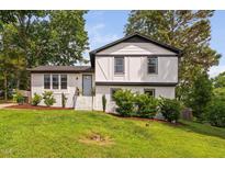 Charming two-story white brick home with black trim, well-manicured lawn, and lush landscaping at 5400 Kaplan Dr, Raleigh, NC 27606