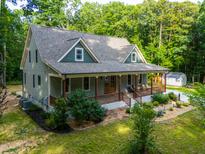 Charming home featuring a covered front porch, beautiful landscaping, and a lush, wooded surrounding at 698 Maple Springs Ln, Bear Creek, NC 27207