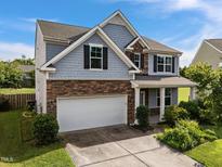 Beautiful two-story home with stone and siding exterior, a two-car garage and manicured landscaping at 7 Faircroft Ct, Durham, NC 27703