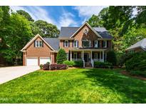 Charming brick home featuring a lush green lawn, two-car garage, and mature trees at 7620 Rainwater Rd, Raleigh, NC 27615