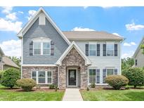 Charming two-story home with a beautifully landscaped yard and a mix of stone and siding facade at 1148 Survada Ln, Morrisville, NC 27560