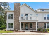 Charming two-story exterior showing a combination of brick and white siding with a quaint balcony and well-maintained landscaping at 11548 Helmond Way # 104, Raleigh, NC 27617