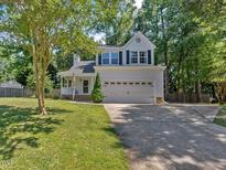 Charming two-story home with a two-car garage, well-manicured lawn, and mature trees at 221 Antique Lace Way, Holly Springs, NC 27540