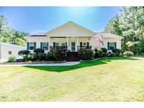 Charming single-story home with a well-manicured lawn, flowerbeds and inviting front porch at 3564 Lower Moncure Rd, Sanford, NC 27330