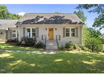 Charming brick home featuring a natural wood front door, inviting curb appeal, and manicured landscaping at 405 E Millbrook Rd, Raleigh, NC 27609