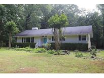 Charming single-story home with a lush green lawn, mature trees, and a lovely blue front door at 5112 Stephens Ln, Durham, NC 27712