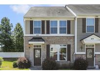 Inviting two-story home with brick facade and well-manicured lawn in a townhome community at 523 Berry Chase Way, Cary, NC 27519