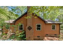 Charming home featuring a brick chimney and rustic wood siding, nestled amidst lush greenery at 5315 Mccormick Rd, Durham, NC 27713