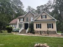 Charming two-story home with stone accents, a well-manicured lawn, and beautiful landscaping at 6225 Acorn Ridge Trl, Hillsborough, NC 27278
