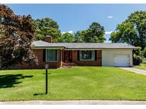 Charming brick home with a well-manicured front lawn, mature trees, and a driveway leading to a one-car garage at 712 E Horne St, Clayton, NC 27520