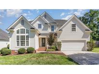 Charming two-story traditional home featuring a manicured lawn, attached garage, and welcoming entrance with brick steps at 103 Equestrian Ct, Cary, NC 27513