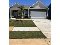 Charming home featuring a covered porch, two-car garage, and freshly laid sod at 144 N Keatts Winner Ct, Wilson's Mills, NC 27520