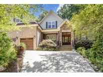 Charming brick home featuring an attached garage, stone accents, and professionally landscaped yard at 150 Luxorwind Dr, Garner, NC 27529