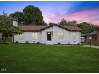 Charming home with a brick exterior, well-manicured lawn, and a picturesque sunset backdrop at 1709 Hawthorne Lane Ln, Burlington, NC 27215