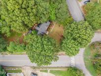 Charming home with a gray roof nestled among mature trees and manicured landscaping at 301 N King Charles Rd, Raleigh, NC 27610