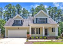 Charming home with a manicured lawn and a two-car garage, nestled among tall trees at 305 Avent Meadows Ln, Holly Springs, NC 27540