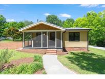 Charming bungalow with a screened-in porch, yellow siding, and landscaped front yard at 3213 Mid Pines Rd, Raleigh, NC 27606