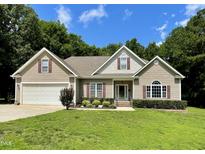 Charming single-Gathering home featuring a well-manicured lawn, attached garage, and inviting front porch at 55 Ridge Haven Dr, Louisburg, NC 27549