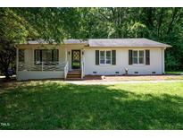Charming single-story home with white painted brick, green shutters, manicured lawn, and inviting front porch at 6501 Battleford Dr, Raleigh, NC 27613