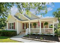 Charming single Gathering home showcasing a cozy porch with an American flag and lovely landscaping at 86 Basswood Cir, Willow Springs, NC 27592
