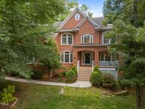 Charming red brick two-story home featuring a welcoming front porch and professionally landscaped yard at 100 Redfoot Run Rd, Chapel Hill, NC 27516