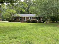 Charming brick home featuring black shutters, a well-manicured lawn, and mature trees in a serene setting at 108 Shadowbrook Dr, Hillsborough, NC 27278