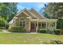 Charming stone and beige home with a covered front porch and professionally landscaped lawn at 126 Captains Ct, Durham, NC 27712