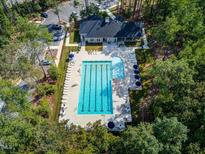 Aerial view of a community pool with lounge chairs and umbrellas surrounded by trees at 1471 Carlton Links Dr, Fuquay Varina, NC 27526