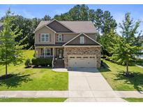 Charming two-story home featuring a stone-accented facade, well-maintained landscaping, and a two-car garage at 175 Hawkesburg Dr, Clayton, NC 27527