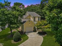 Charming two-story home with yellow siding, mature trees, and a curved driveway at 20 Nicklaus Way, Clayton, NC 27520