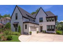 Striking white painted brick two-story home with black trim, black roof, manicured landscaping and a driveway at 2114 Cowper Dr, Raleigh, NC 27608