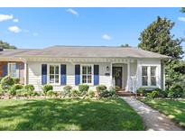 Charming home exterior with manicured lawn, blue shutters, and mature landscaping at 2617 Cottage Cir, Raleigh, NC 27613