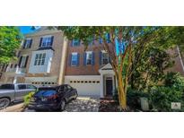 Three-story brick townhome featuring an attached two-car garage and mature landscaping at 332 Bridgegate Dr, Cary, NC 27519