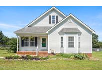 Charming home featuring white siding, a cozy front porch, and manicured landscaping at 3831 Abattoir Rd, Angier, NC 27501