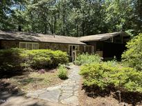 Charming stone home featuring a stone walkway and lush landscaping, nestled in a wooded setting at 5836 Sandstone Dr, Durham, NC 27713