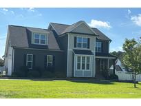 Two-story home with dark siding, a gray shingled roof, manicured lawn, and manicured shrubs at the foundation at 644 Wall Rd, Wendell, NC 27591