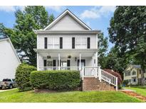 Charming two-story home with white siding, black shutters, front porch, and landscaped yard at 8513 Buscot Ct, Raleigh, NC 27615