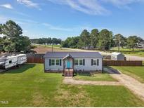 Charming gray home features a well-manicured lawn and a striking blue front door, exuding curb appeal at 10 Wilders Ln, Louisburg, NC 27549