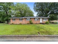 Charming brick ranch-style home with mature trees and a lush green lawn at 1402 Tarleton Ave, Burlington, NC 27215