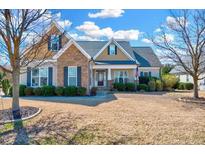 Charming two-story home with a mix of stone and siding, a well-maintained lawn and mature trees at 1624 Struble Cir, Willow Springs, NC 27592