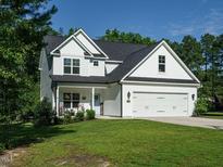 Charming two-story home boasts a manicured lawn, attached two car garage, and cozy front porch perfect for relaxing at 221 Stella Way, Cameron, NC 28326